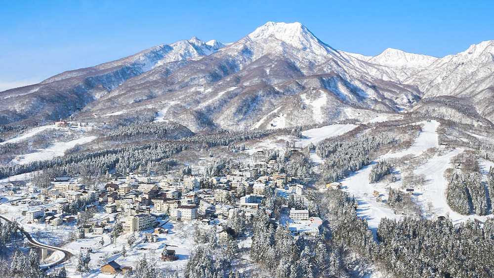 Drone view of Akakkura Onsen with houses at the base of Mt Myoko